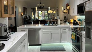 A modern kitchen with white cabinetry, stainless steel appliances, and a central island. - BEST in Monterey Country Club-South-New Remodel-2024-STR or monthly-185 Gran Via (Palm Desert)