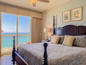 A bedroom with a large bed, a nightstand, a lamp, and framed pictures on the wall.