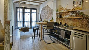 Una cocina con pisos de madera, pared de ladrillo y un comedor con mesa y sillas.