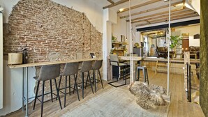 Un interior rústico con paredes de ladrillo visto, una zona de bar con taburetes y un rincón de estar acogedor con una manta de piel.