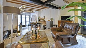 Una sala de estar moderna con muebles de cuero, una mesa de centro de vidrio y una cocina al fondo.