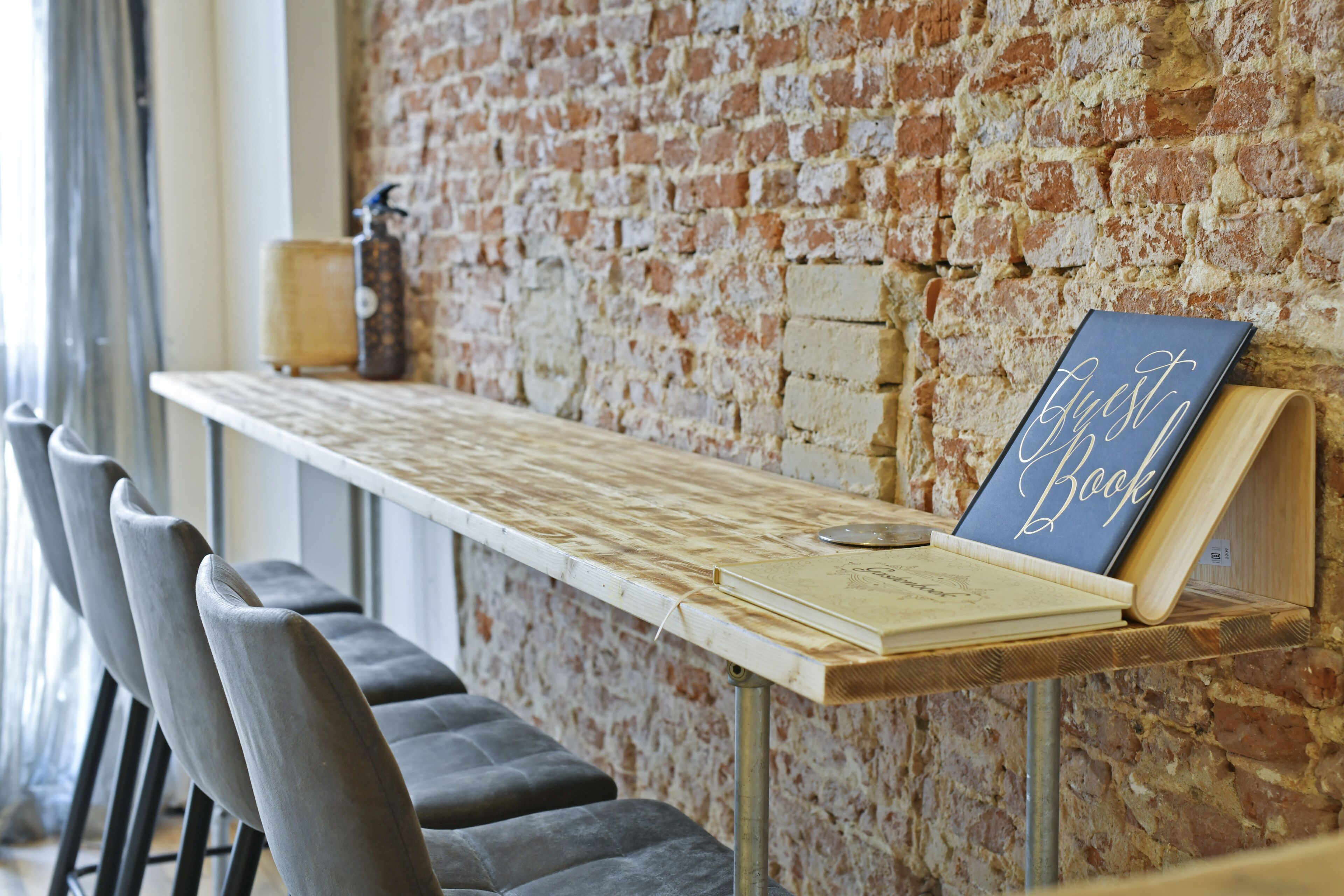 Een lange houten tafel met een boek dat ‘Just Book’ heet en een lamp erop.