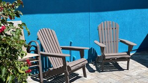 Zwei Adirondack-Stühle und ein Tisch vor einer blauen Wand.