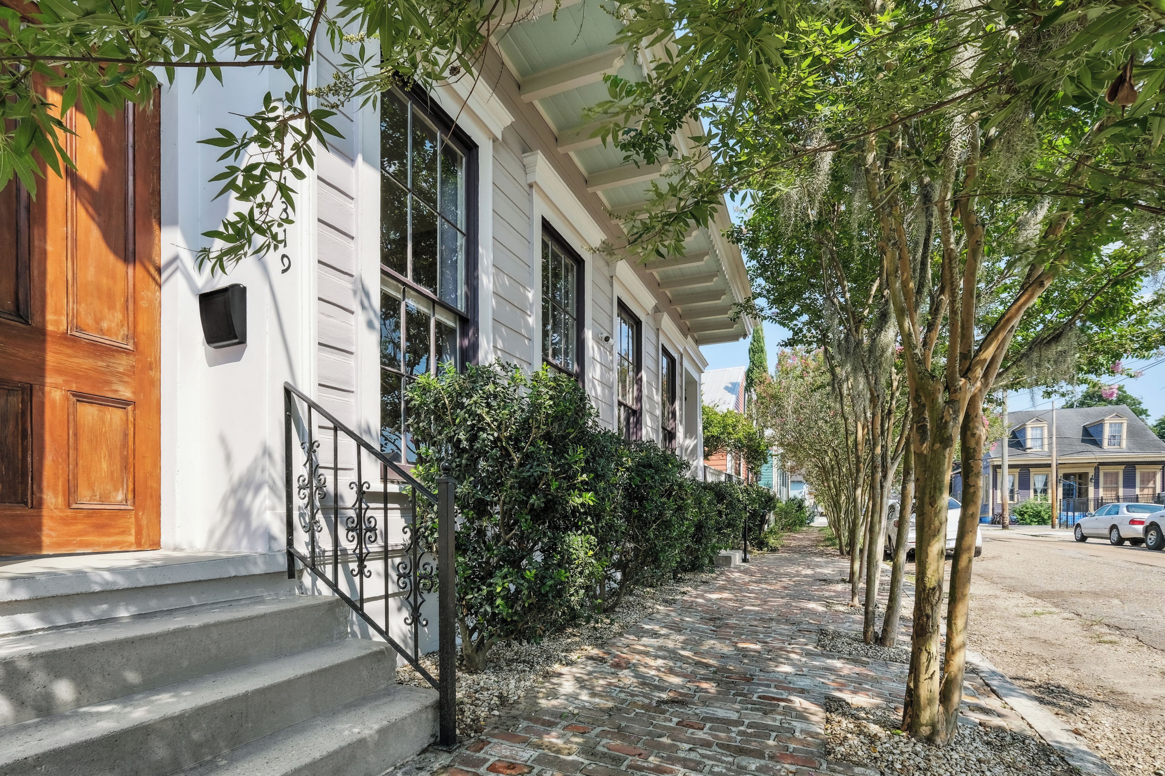 A residential building with a front entrance, a stone-paved pathway, and a row of trees.