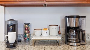 Eine Küchenarbeitsplatte mit Kaffeemaschine, einer Waage und Behältern mit den Aufschriften 'Zucker' und 'Tee'.