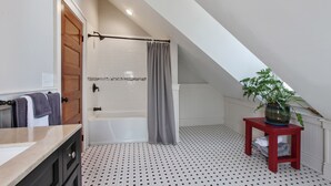 Ein modernes Badezimmer mit Badewanne, Dusche und einem kleinen roten Tisch mit einer Pflanze.