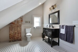 A bathroom with a white toilet, black and white patterned floor, a black vanity with a mirror, and a towel rack. - Upscale and Historic, 2 blocks to Streetcar, 4 to French Quarter, 6 to Frenchmen (New Orleans)