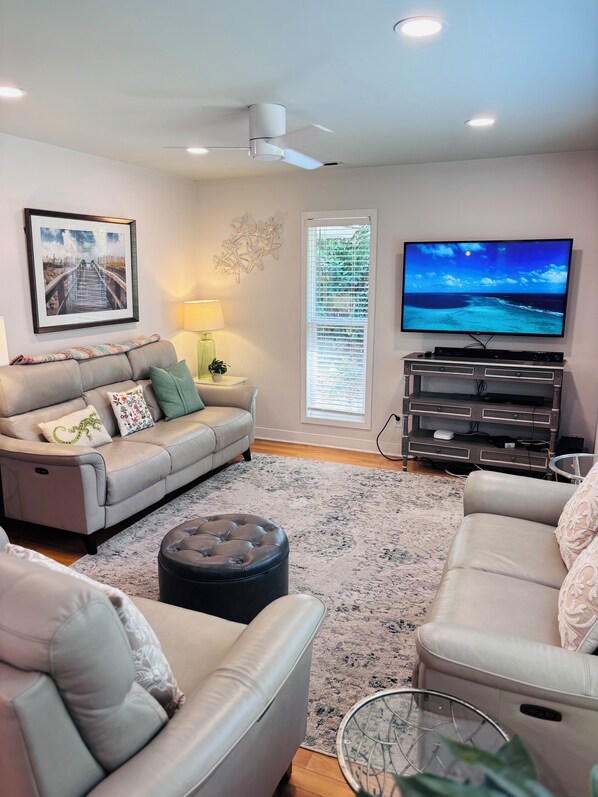A living room with a sofa, ottoman, TV, and entertainment unit.