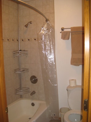 Tina con regadera, toallas, papel de baño