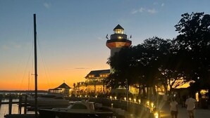 A waterfront scene with a lighthouse, boats docked, and a walkway with people. - 3BR 2.5 BA, short walk or 5 min bike to beach w/ cart, chairs, pools, sm. dog (Hilton Head Island)