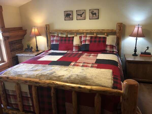 A bed with a plaid quilt, wooden headboard, and two bedside lamps. - Authentic, charming Western Ranch (Bondurant)