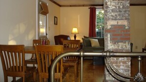 A dining area with wooden chairs and a table, a sofa, and a lamp.