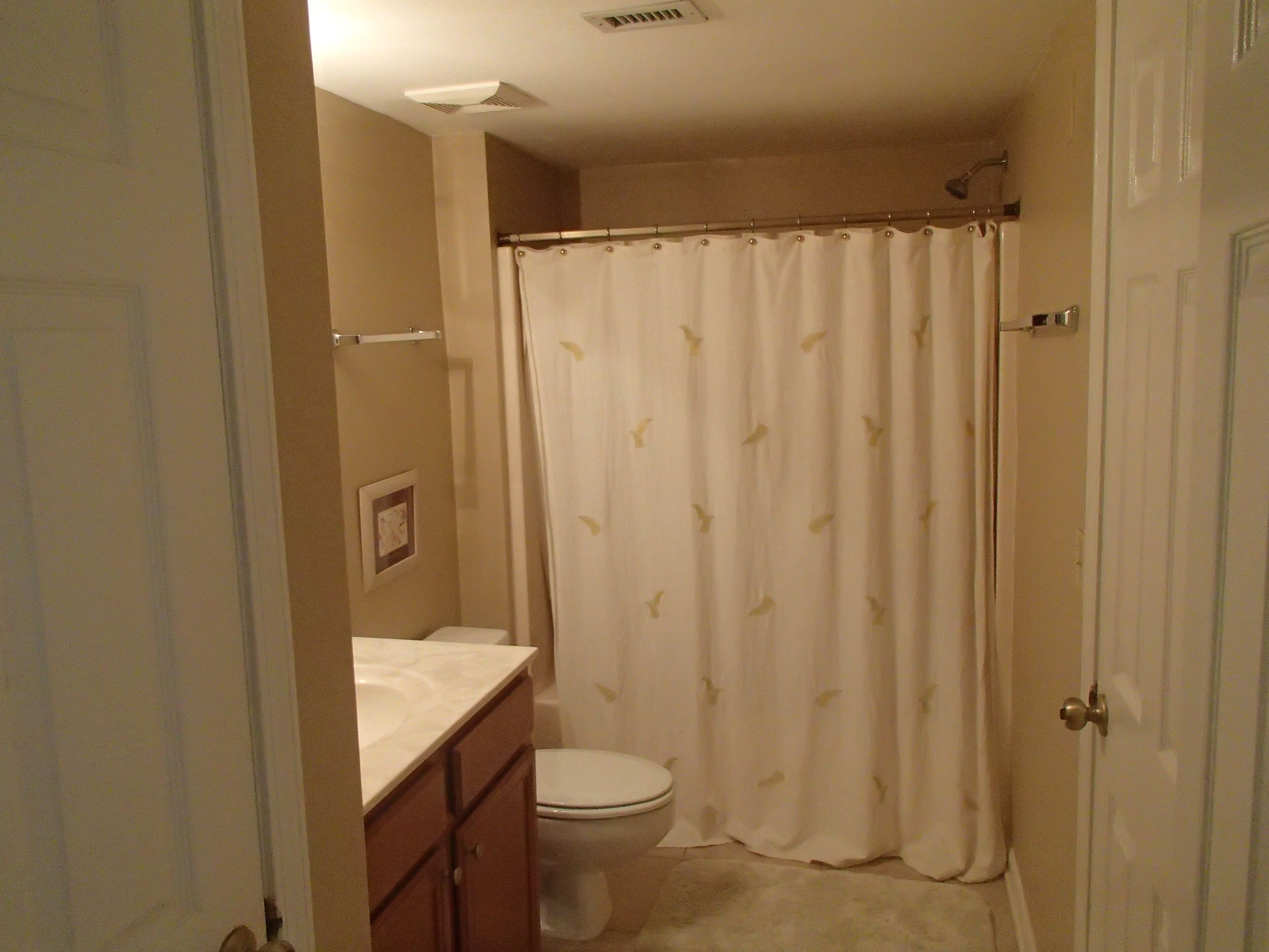 A bathroom with a toilet, a shower curtain, and a sink.