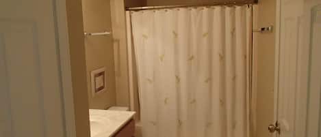 A bathroom with a toilet, a shower curtain, and a sink.
