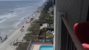 A pool area with lounge chairs, a small pool, and a beach view.