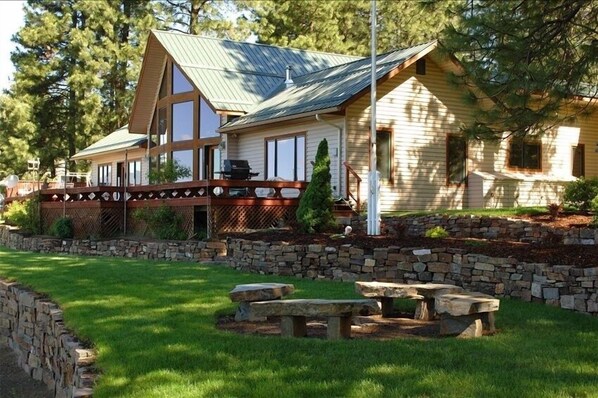 Enjoy outdoor dining on the spacious deck surrounded by a beautifully maintained lawn and stone retaining wall.