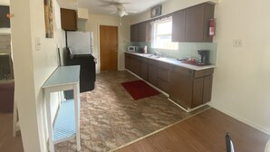 Una cucina con mobili in legno, un forno a microonde, un fornello e un tappeto rosso.