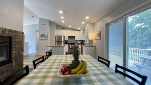 Une cuisine moderne avec des meubles blancs, un îlot central et un coin repas agrémenté d’une nappe à carreaux.