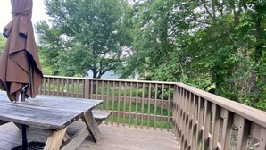 Une terrasse en bois avec une table et des chaises, entourée d’une balustrade en bois.