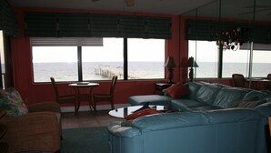 Ein Wohnzimmer mit einem großen Fenster, einem blauen Sofa, einem kleinen Tisch und einem Sessel.