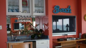 Eine Küche mit Essbereich, ausgestattet mit einem Fernseher, Schränken und einem Schild mit der Aufschrift 'Beach'.