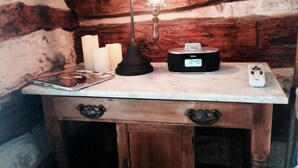 Un escritorio de madera con una lámpara, velas, un reloj, un control remoto y una revista.
