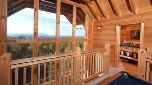 Une cabane en bois avec une table de billard et une vue sur les montagnes.