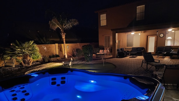Ein Whirlpool mit blauem Licht, umgeben von Gartenmöbeln und einer Palme.