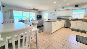 Cozinha com ilha central, armários brancos e vista para o exterior.