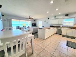 A kitchen with a central island, white cabinetry, and a view to the outside.