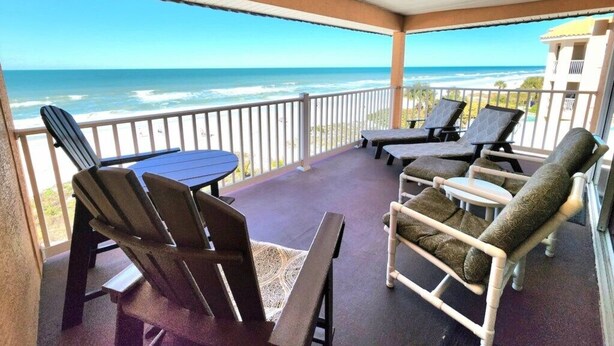 Área externa coberta com vista para o mar, com uma mesa e cadeiras.