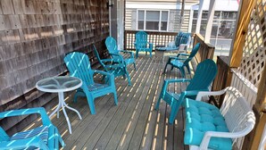 Une terrasse en bois, agrémentée de chaises turquoise et d’une petite table ronde, entourée d’une clôture en bois et d’un treillage.