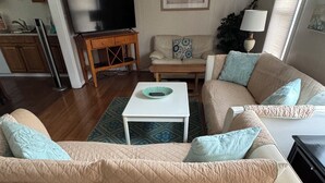 Un salon avec un canapé beige, une table basse blanche et un tapis à motifs.