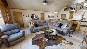 A spacious living room with a large sectional sofa, a round coffee table, and a cowhide rug.
