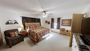 A bedroom with a bed, a chair, a desk, a ceiling fan, and a window with curtains.