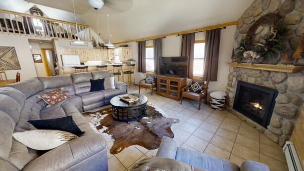 A spacious living room with a stone fireplace, a large leather sofa, and a rustic coffee table.