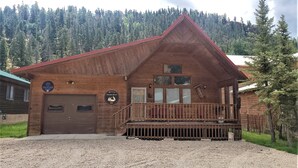 A wooden cabin with a red roof, a front porch, and a sign indicating it is a vacation property.