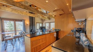 A modern kitchen with a wooden island, built-in appliances, and a large window overlooking a deck. - 2BR 2BA In Town, Walkable, Pet-Friendly, Fireplace, Views! (Crested Butte)