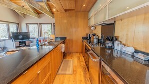 A modern kitchen with wooden cabinetry, a central island, and a built-in stove. - 2BR 2BA In Town, Walkable, Pet-Friendly, Fireplace, Views! (Crested Butte)