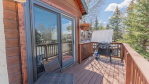 A wooden deck with a sliding glass door, a grill, and a hanging flower basket. - 2BR 2BA In Town, Walkable, Pet-Friendly, Fireplace, Views! (Crested Butte)