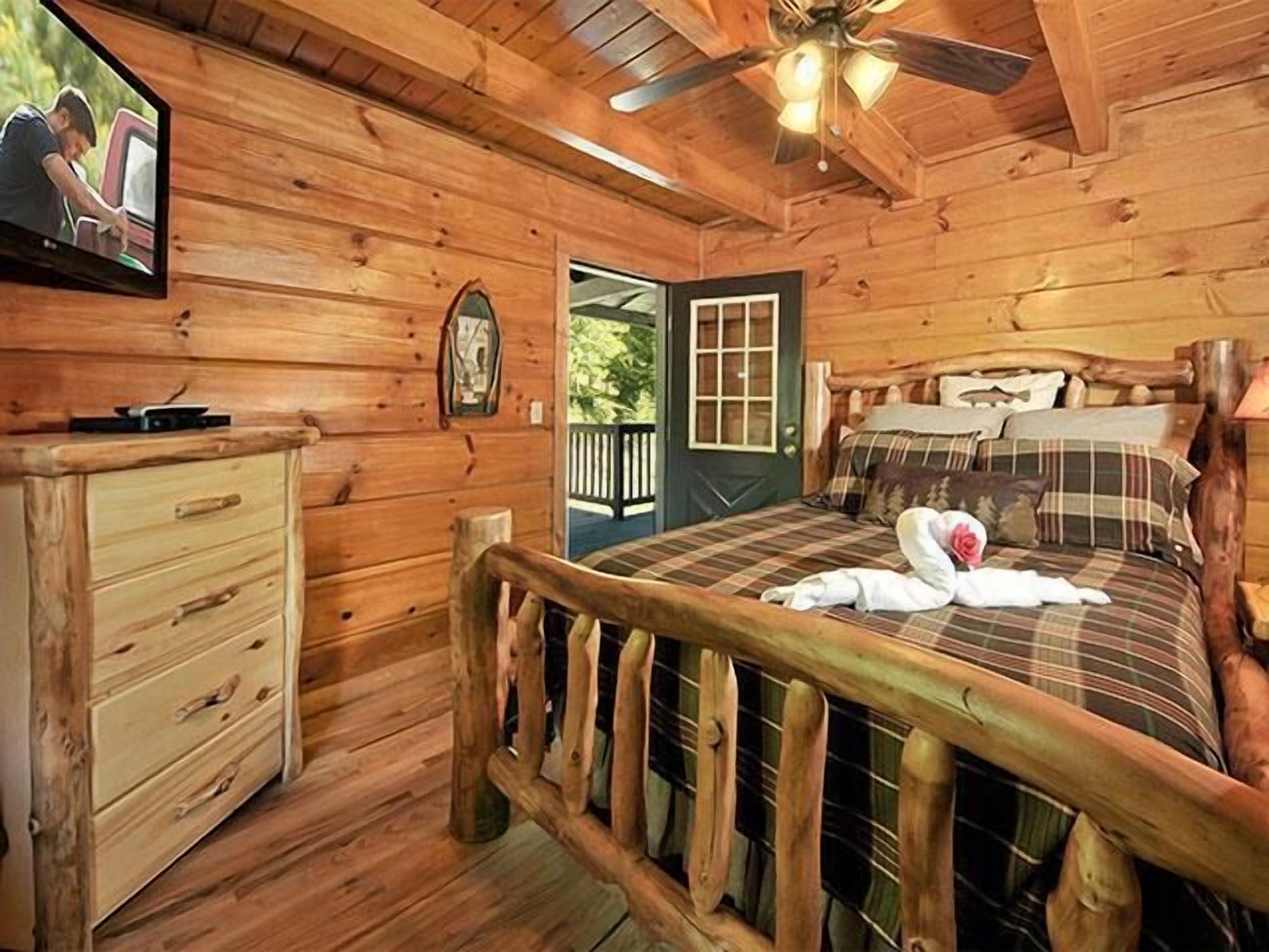 Une chambre dans une cabane en bois, avec un lit, une commode et un téléviseur fixé au mur.