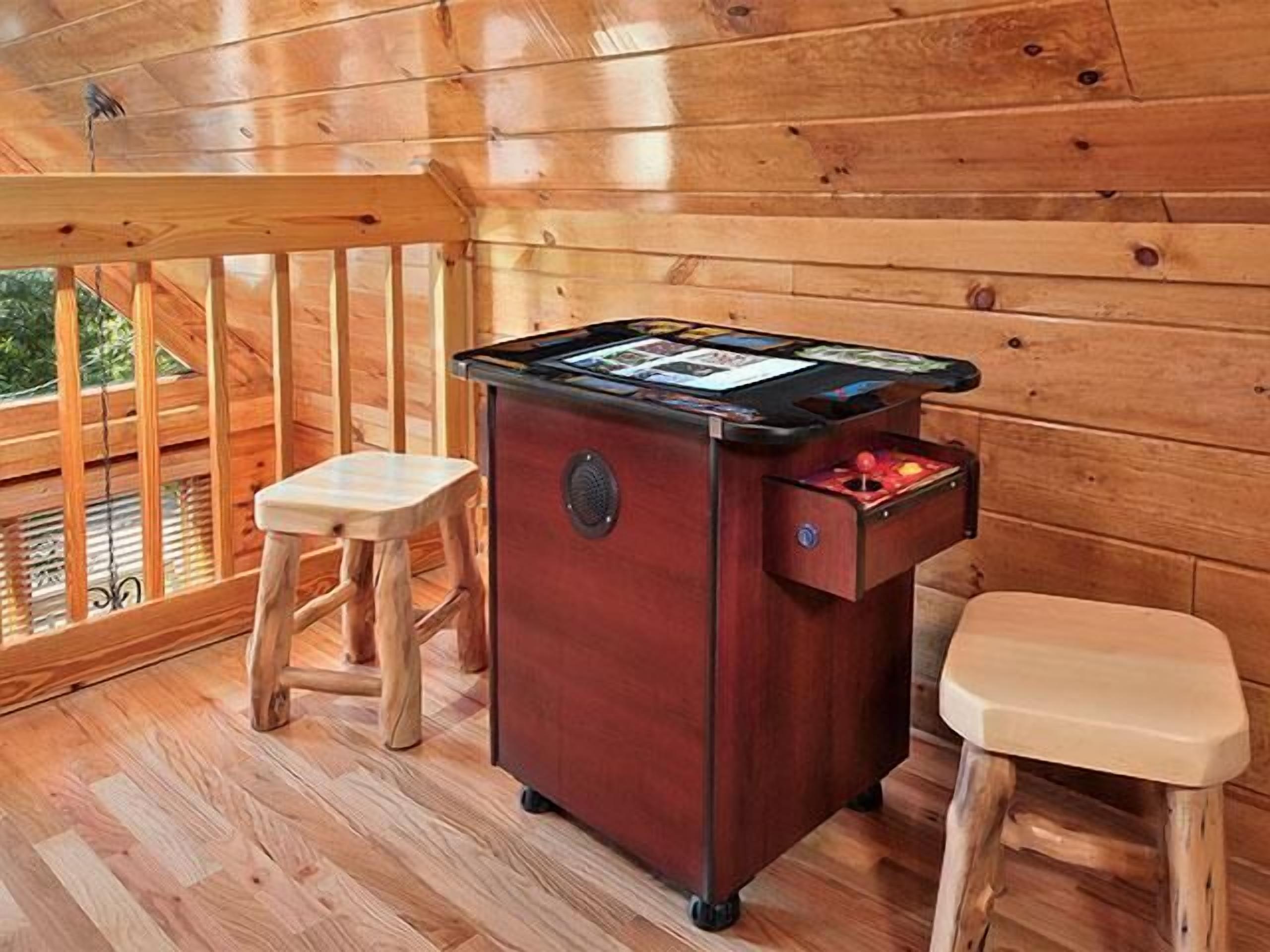 A wooden deck with a pool table, two stools, and a small table with cards.