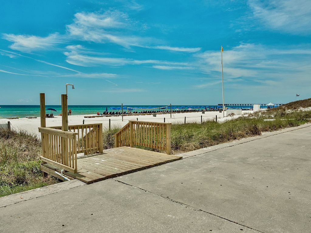 Une plage avec une promenade en bois qui mène à l’eau, un poste de surveillance pour les sauveteurs et une longue jetée qui s’avance dans l’océan.