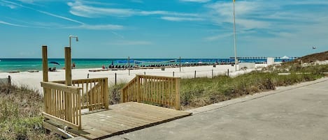 Une plage avec une promenade en bois qui mène à l’eau, un poste de surveillance pour les sauveteurs et une longue jetée qui s’avance dans l’océan.