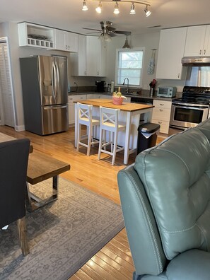 A modern kitchen with a central island, stainless steel appliances, and a ceiling fan. - Charming family vacation cottage, close to the beach on Isle of Palms.  (Isle of Palms)