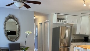 Eine moderne Küche mit einem Edelstahl-Kühlschrank, weißen Schränken und einem Holzes Esstisch mit Stühlen.