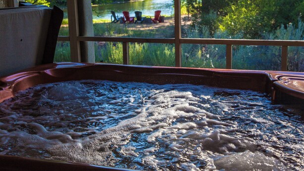 Ein Whirlpool mit Blick auf einen Fluss und Stühlen davor.