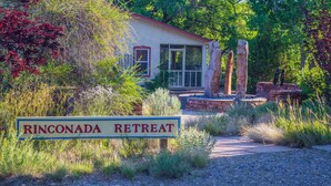 Ein Schild für Rincodada Retreat mit einer Steinmauer und einem Gebäude im Hintergrund.