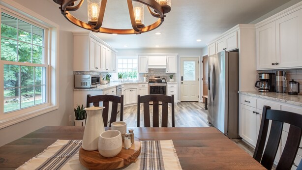 A spacious kitchen with white cabinets, a wooden dining table, and a chandelier. - Kingsway Guesthouse. Come, relax, and enjoy your time in Amish country! (Millersburg)