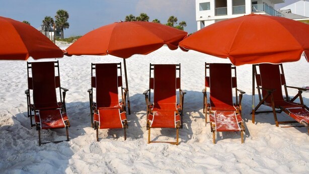 Beach chairs and umbrellas on a sandy beach with a white building in the background. - *PRIVATE BEACH*    *PRIVATE POOL*    *ELEVATOR*    *6 BEACH BIKES* (Panama City)